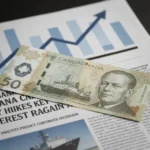 Canadian dollar bills on a newspaper with Bank of Canada interest rate headlines, symbolizing financial impact.