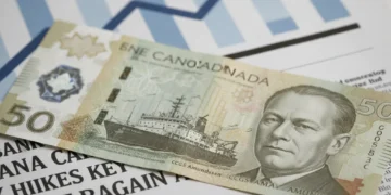 Canadian dollar bills on a newspaper with Bank of Canada interest rate headlines, symbolizing financial impact.